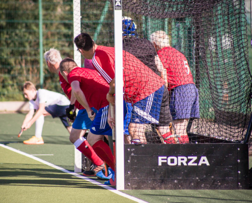 Redditch Hockey Men tucked in the goal to defend a penalty corner in red home kit